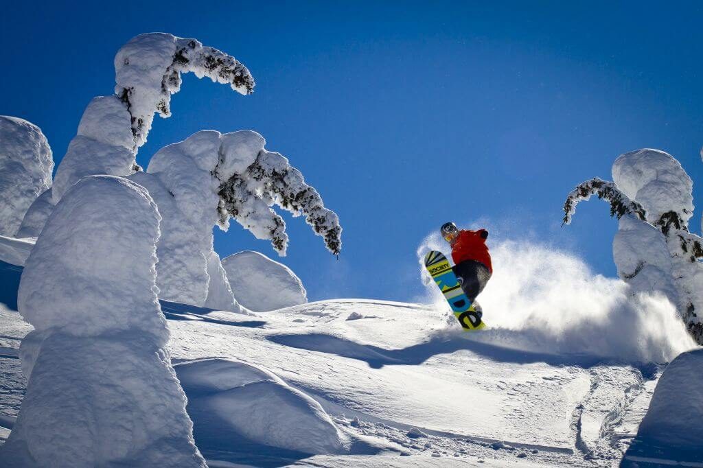 Snowboarder gets fresh tracks through the snow ghosts at Big White Ski Resort